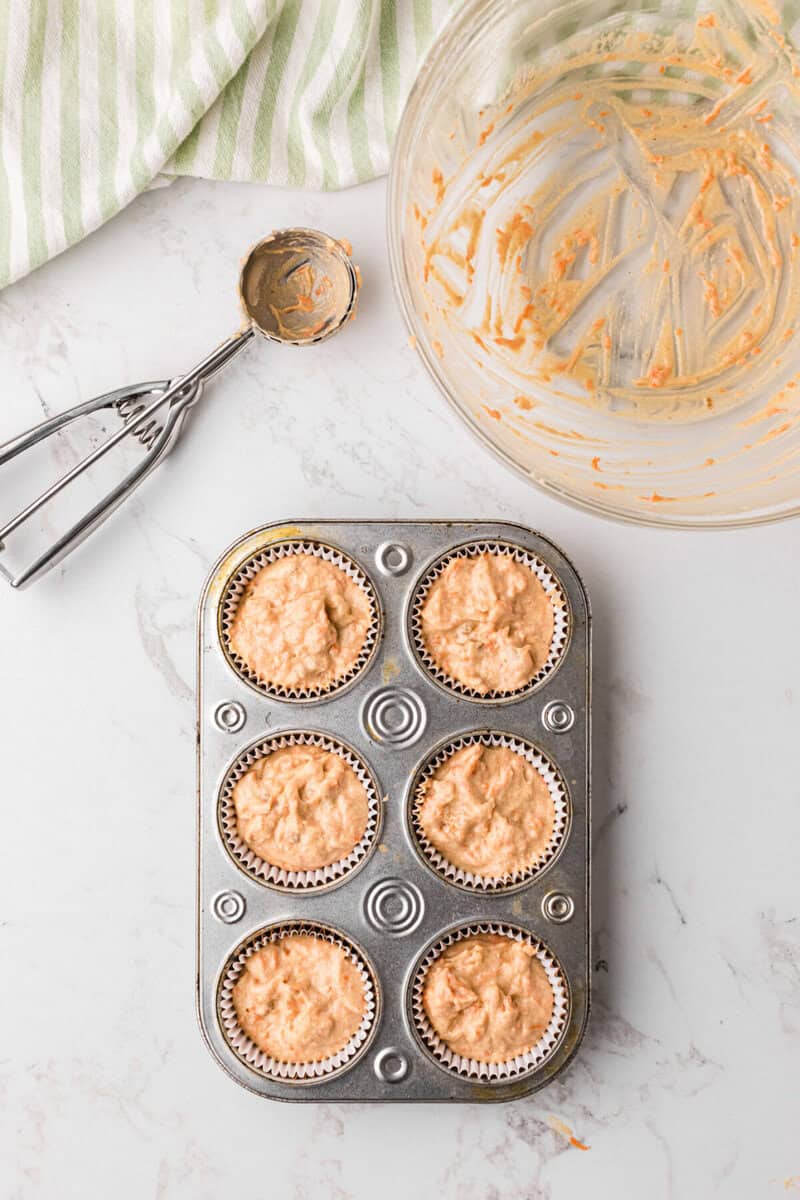 scooping the batter into cupcake liners in a baking pan.