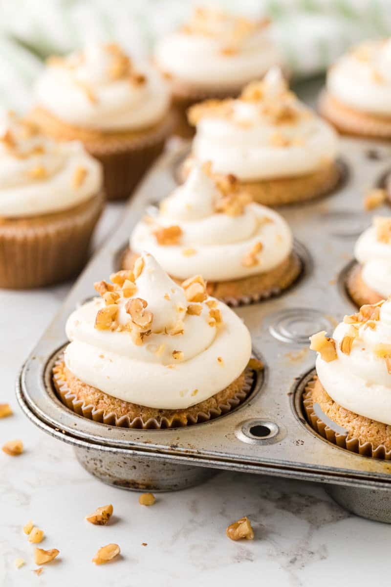 carrot cake cupcakes frosted in the cupcake pan.