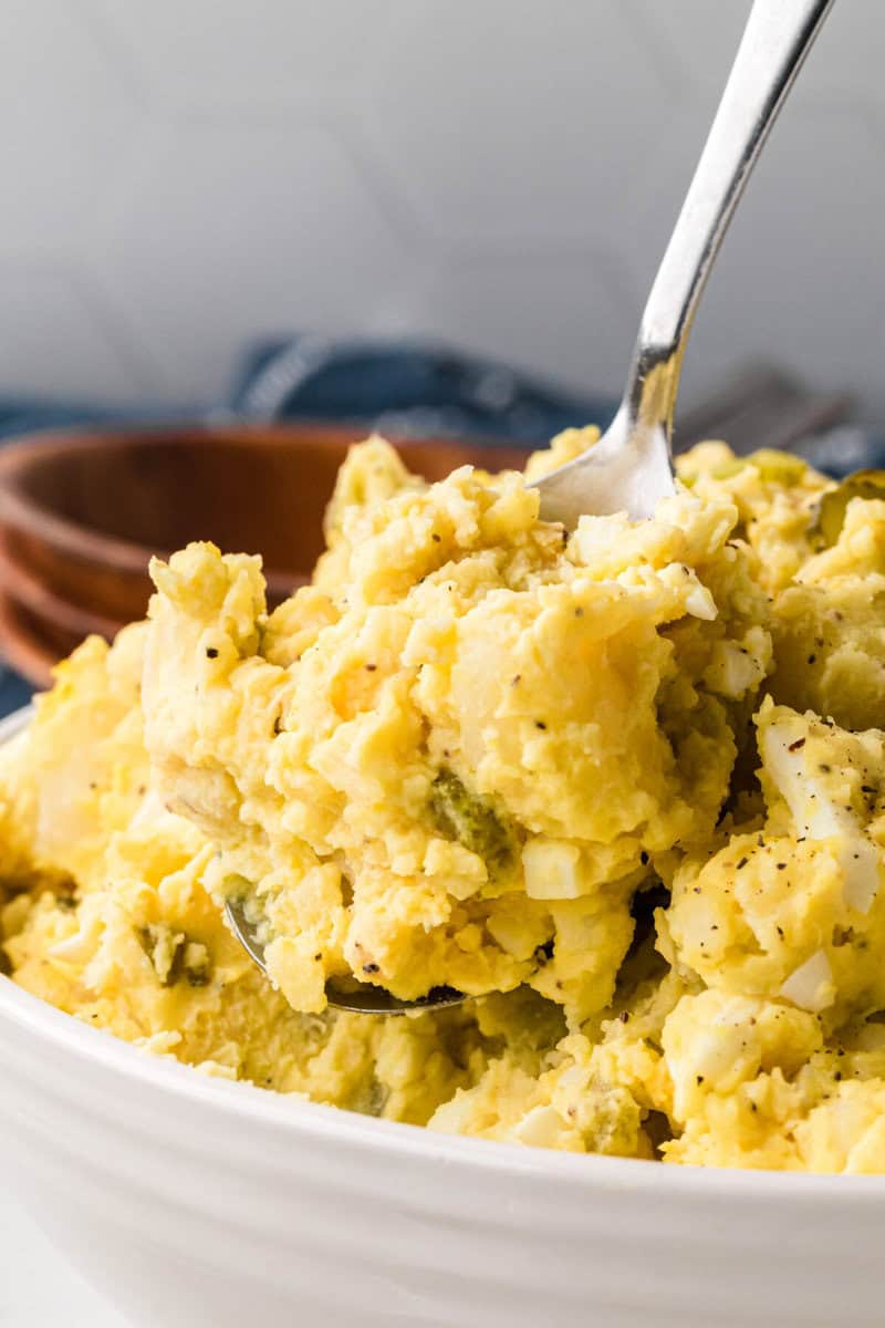 Using a spoon to serve the potato salad.