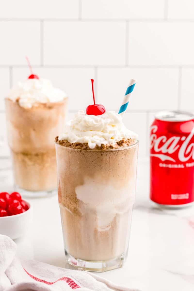 Coke Float in a glass topped with whipped cream and a cherry.
