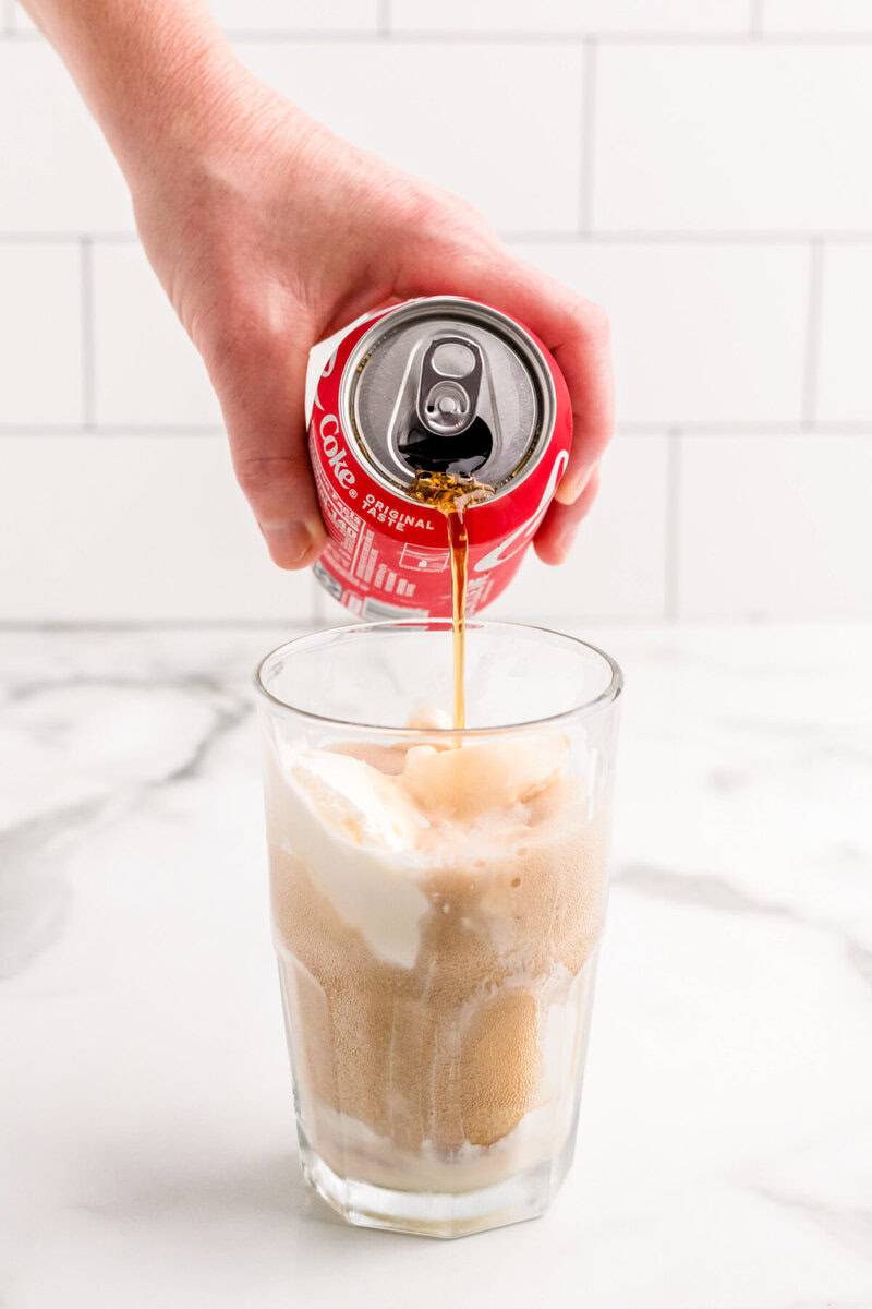 pouring the Coke over the ice cream to make the float.