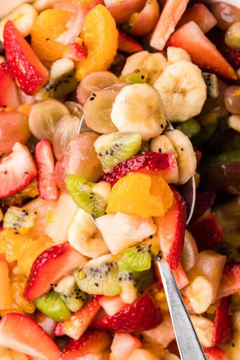 closeup of serving the fruit salad with a metal spoon.
