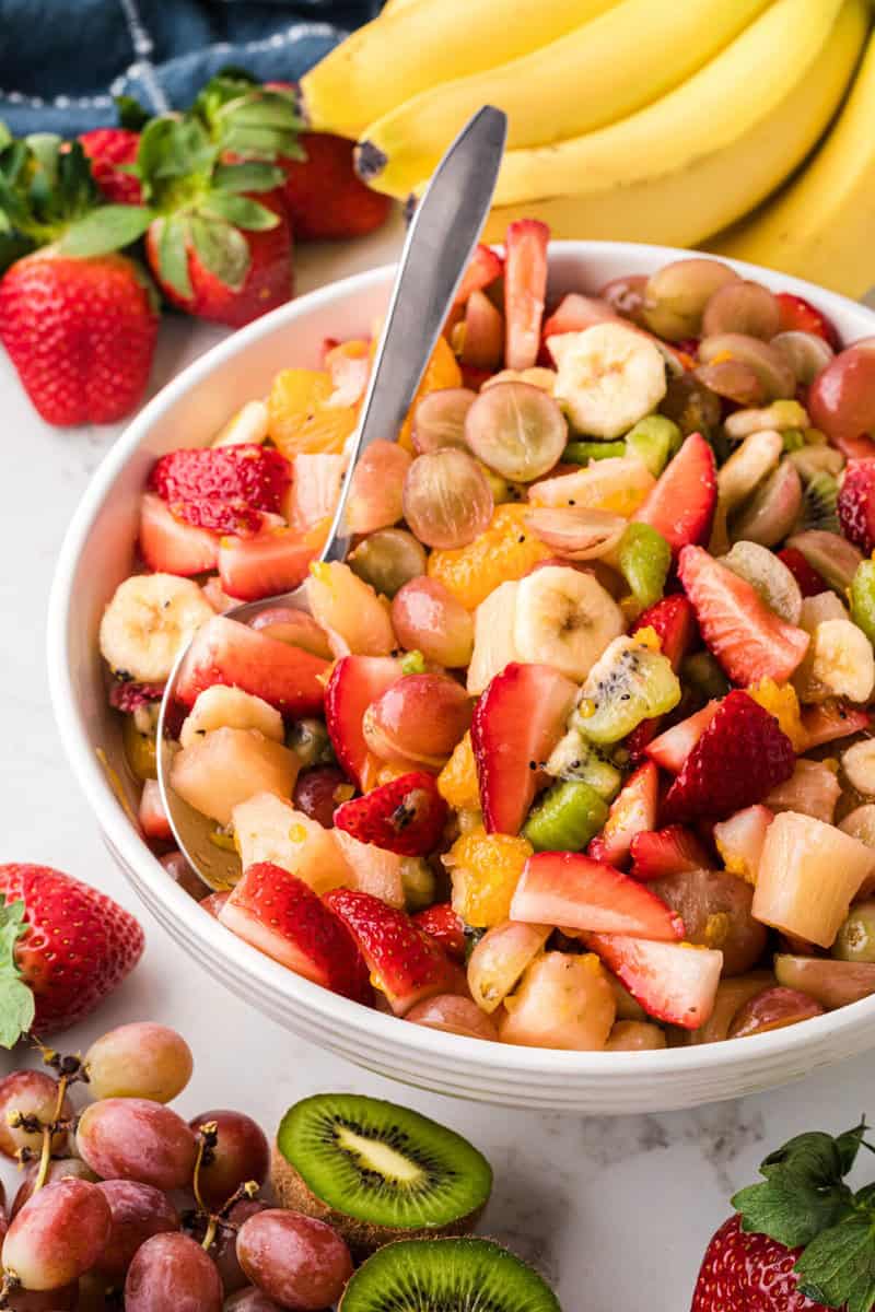 serving the fruit salad with a large metal spoon.