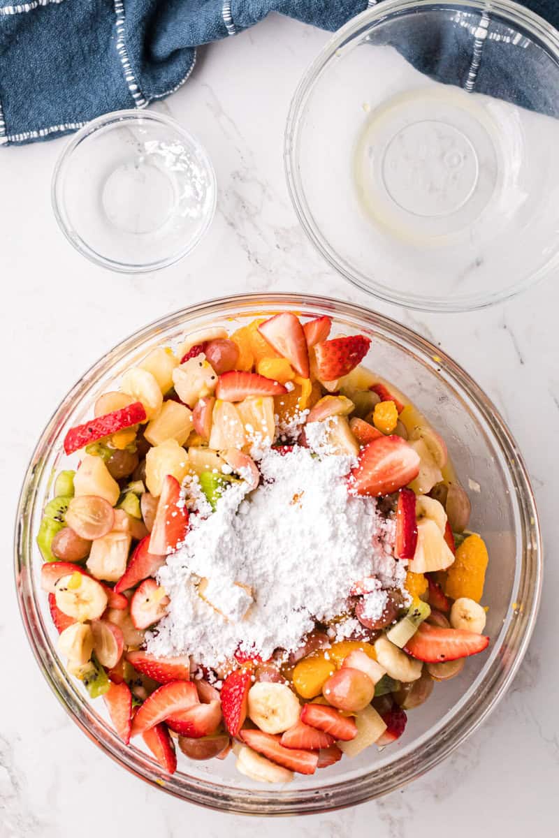 adding the powdered sugar to the fruit salad.