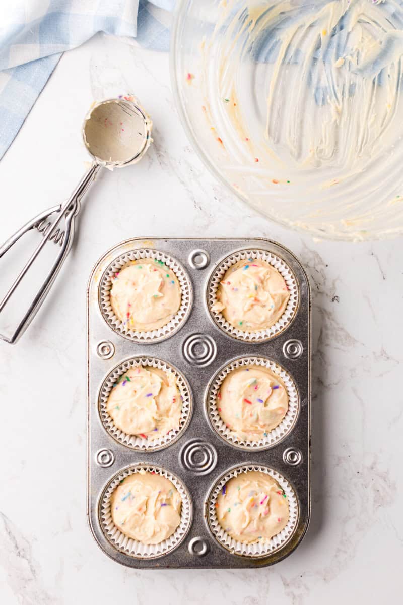 cupcake batter scooped into the cupcake liners in the baking pan.