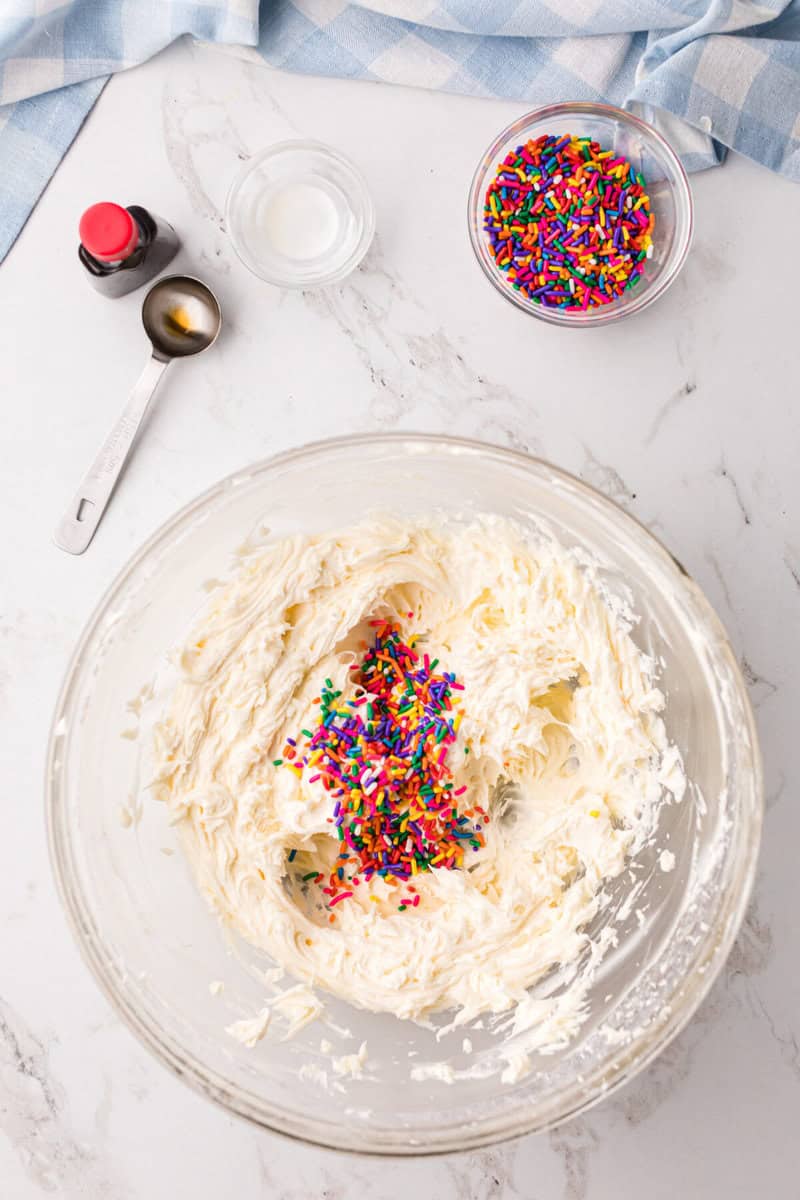 mixing sprinkles into the frosting to make Funfetti Frosting.