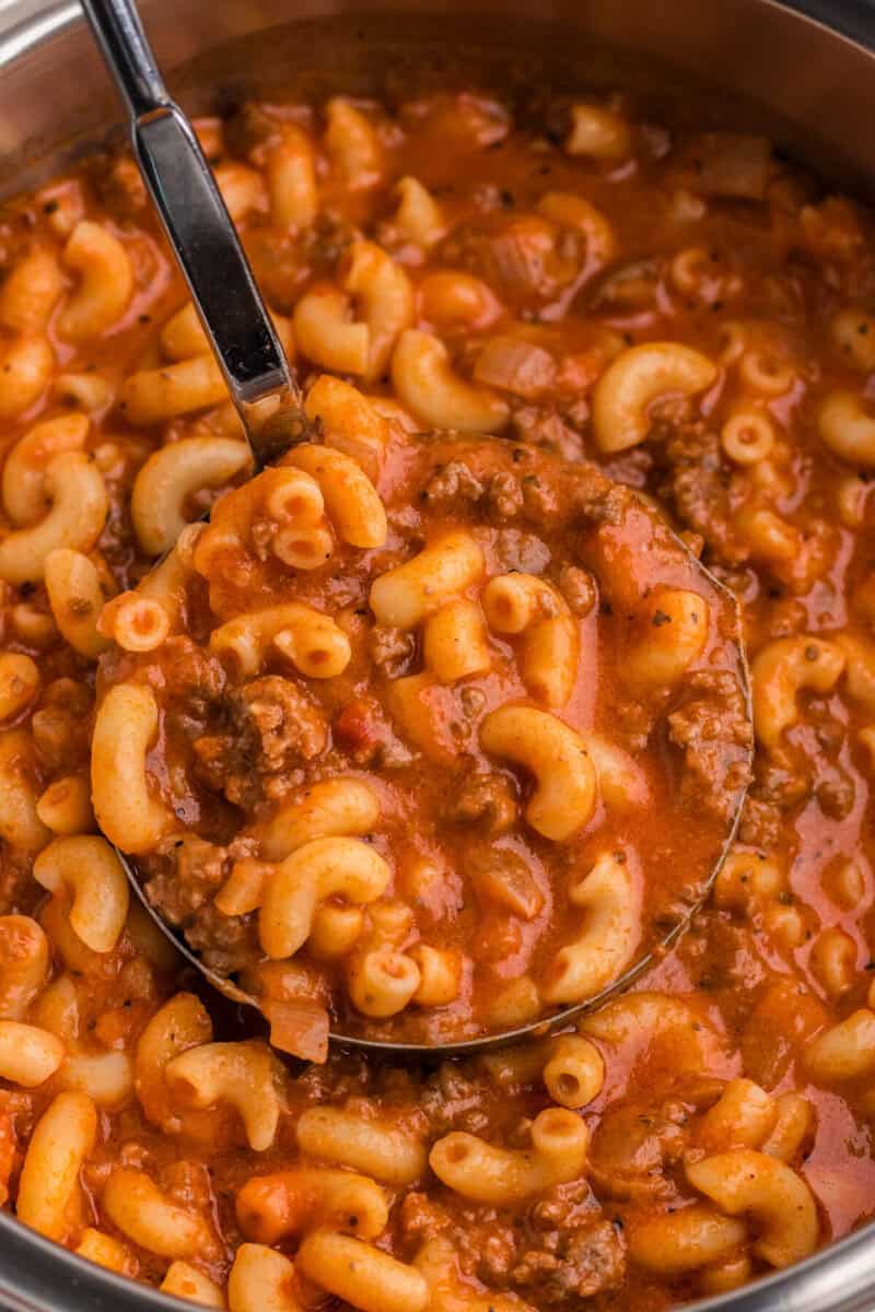 closeup of the beef and macaroni soup being served with a ladle.