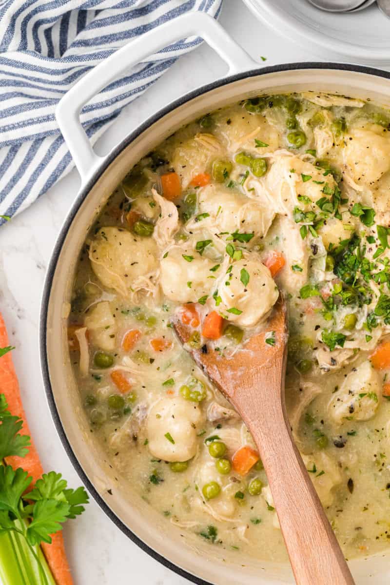 top-down of the Chicken Dumpling Soup being served with a wooden ladle.