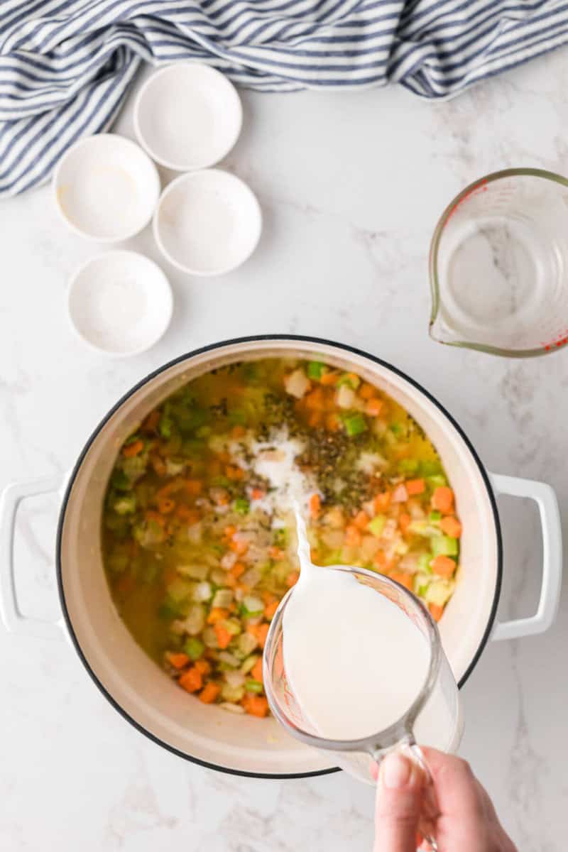 adding the milk to the soup.