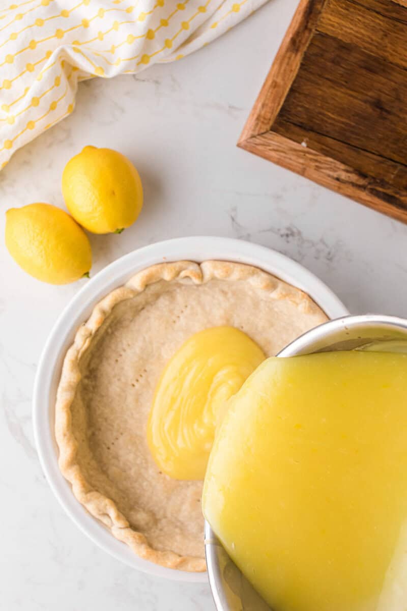 pouring the lemon filling into the baked pie crust.
