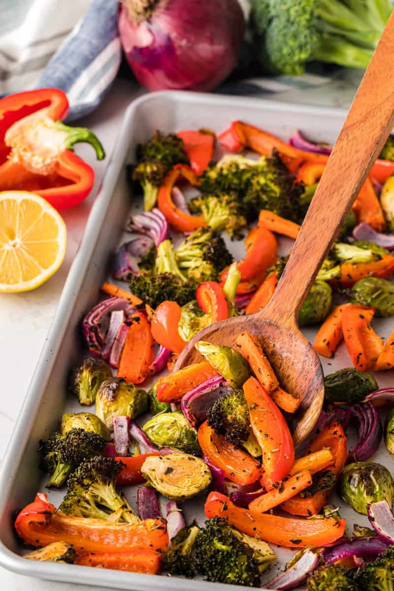 serving the roasted vegetables with a wooden spoon.
