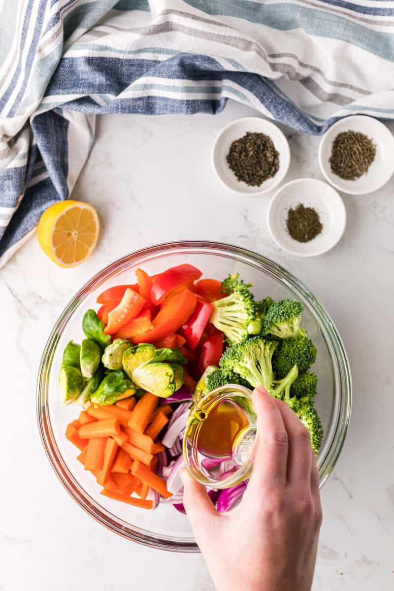 pouring the oil over the vegetables.