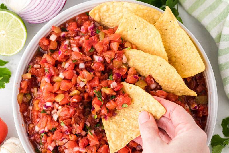using a chip to scoop out homemade salsa.