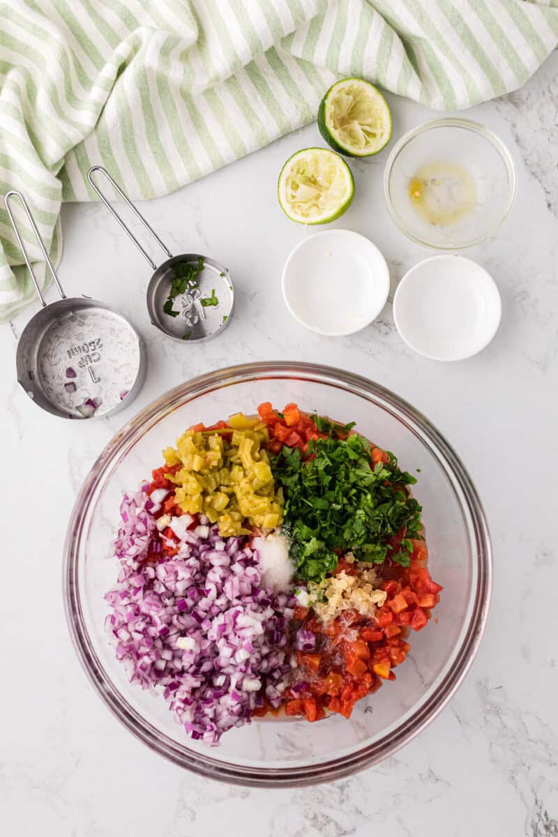 all the ingredients for the salsa in a large glass bowl.