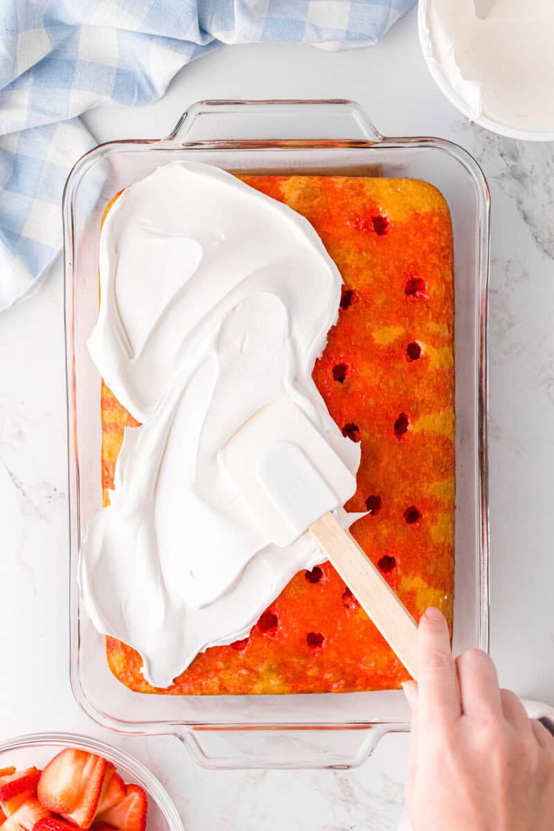 spreading the whipped cream on top of the cake.