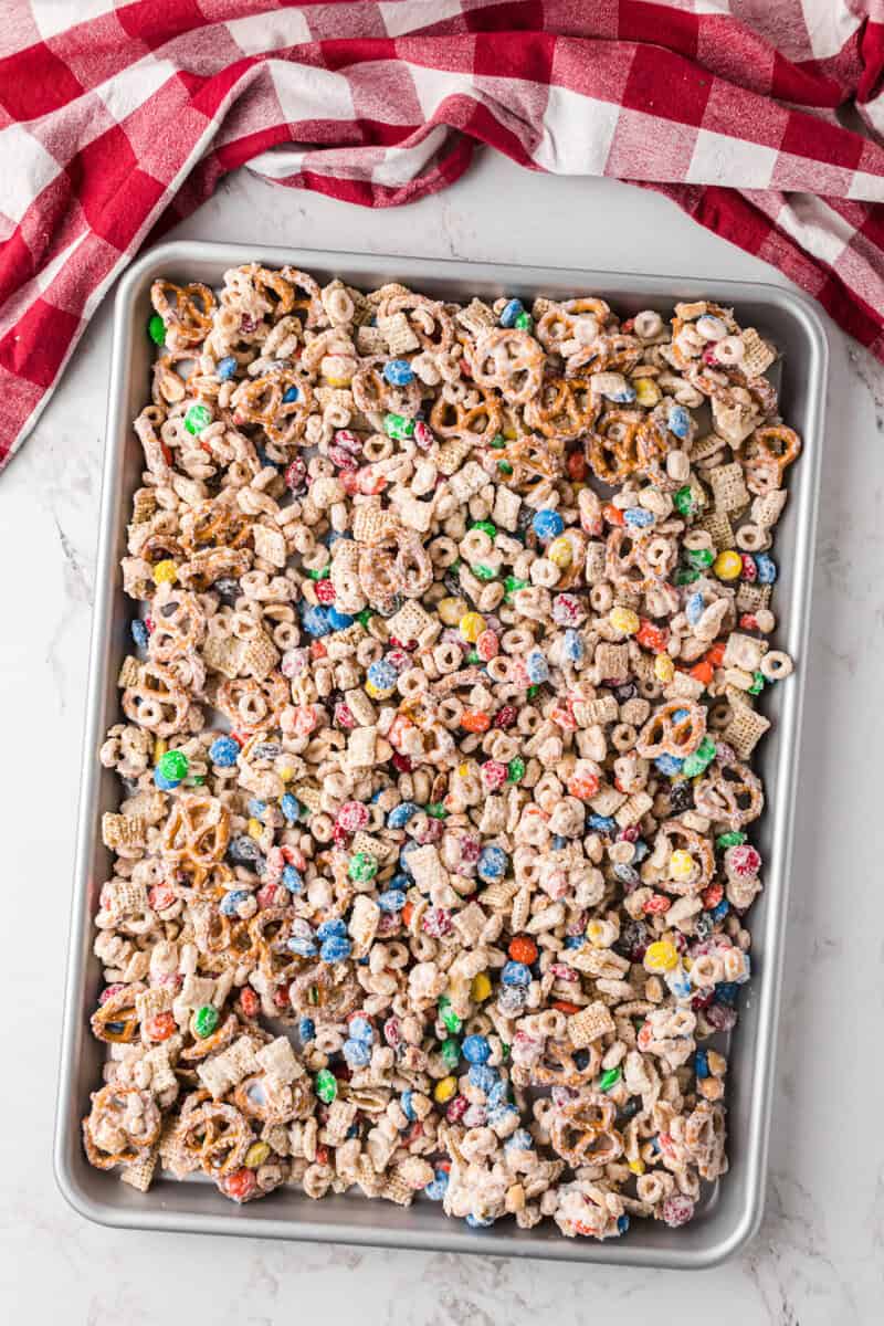 spreading the white trash snack on a baking sheet to allow it to set.