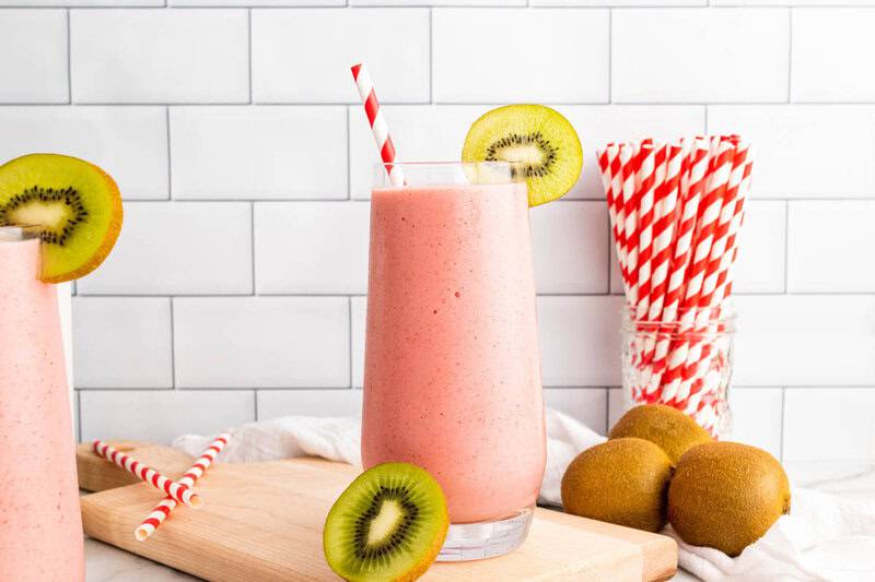 strawberry kiwi smoothie served in a tall glass with a straw in it.