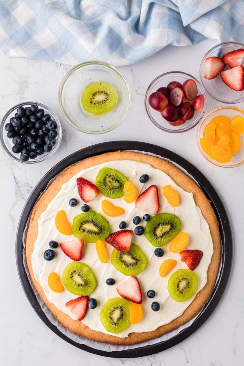 placing the fruit on the fruit pizza.