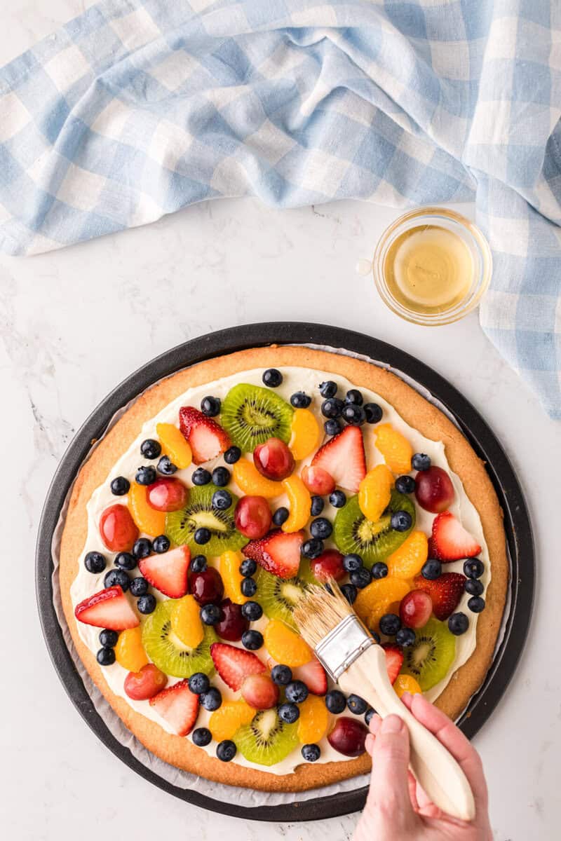 brushing the fruit pizza with the jelly glaze.