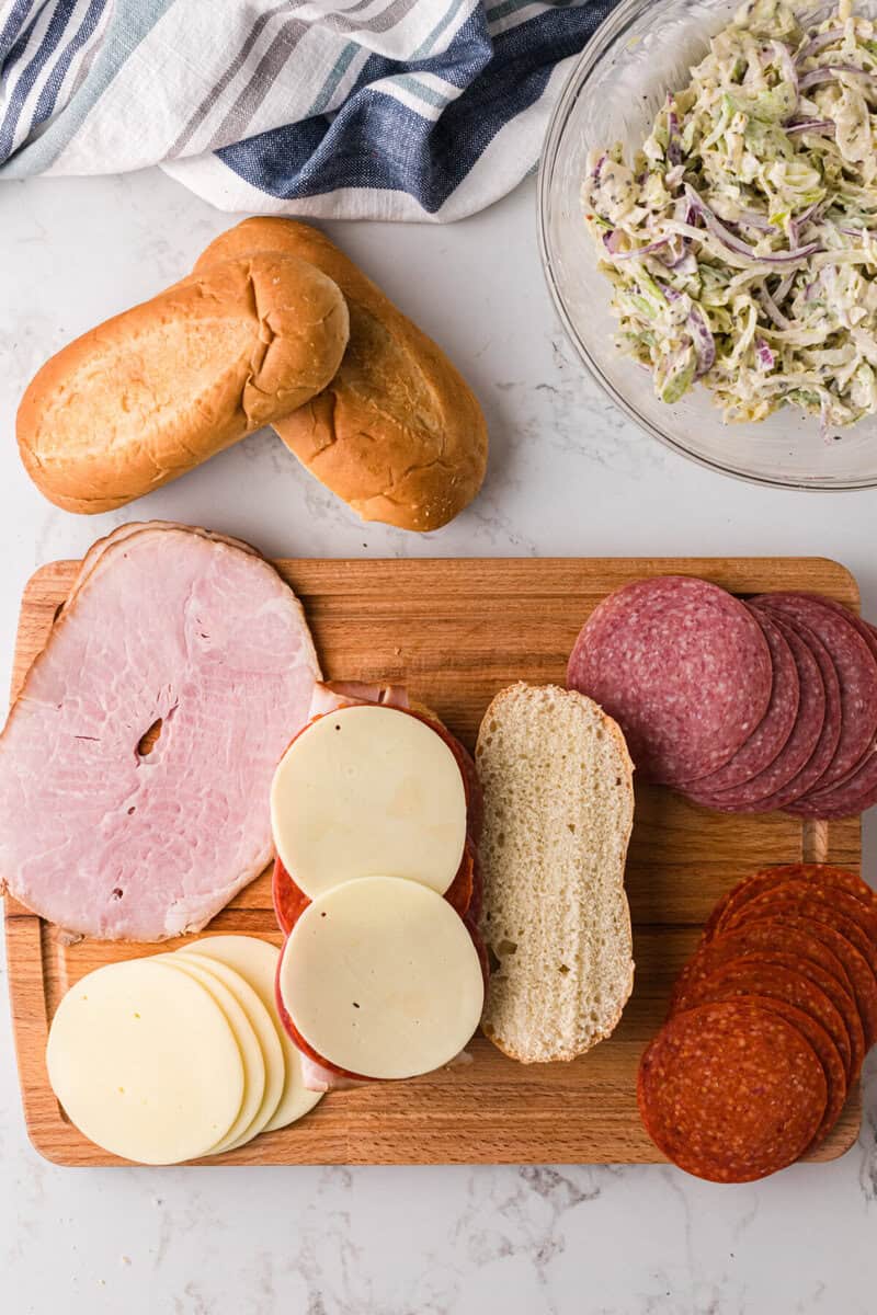 building the grinder sandwich on a wooden board.