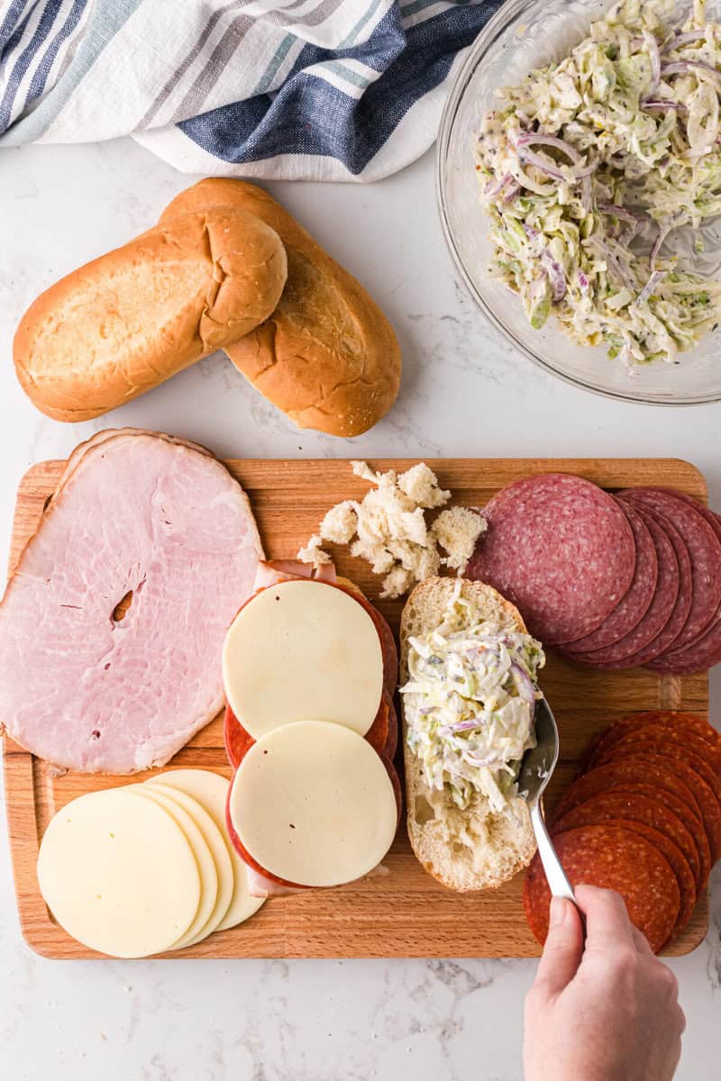 scooping the grinder sandwich dressing salad on top of the bread.