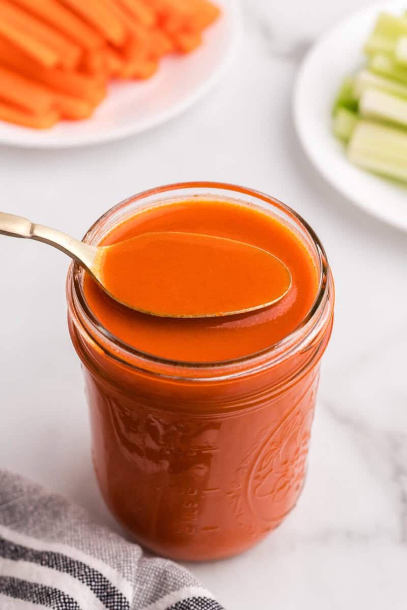 using a spoon to serve the buffalo sauce out of the mason jar.