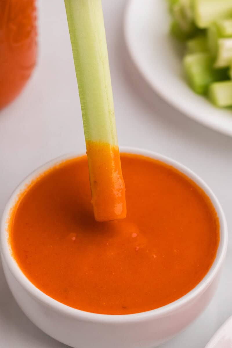 dipping a celery stick into the buffalo sauce.