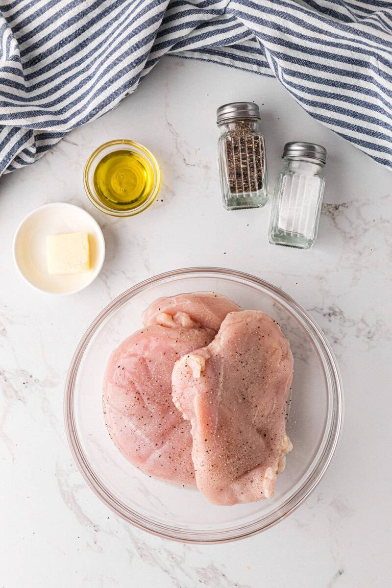 seasoning the chicken breasts in a bowl.