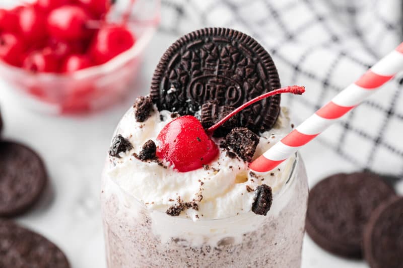 closeup of the top of the Oreo Milkshake topped with whipped cream, cherry and an Oreo.