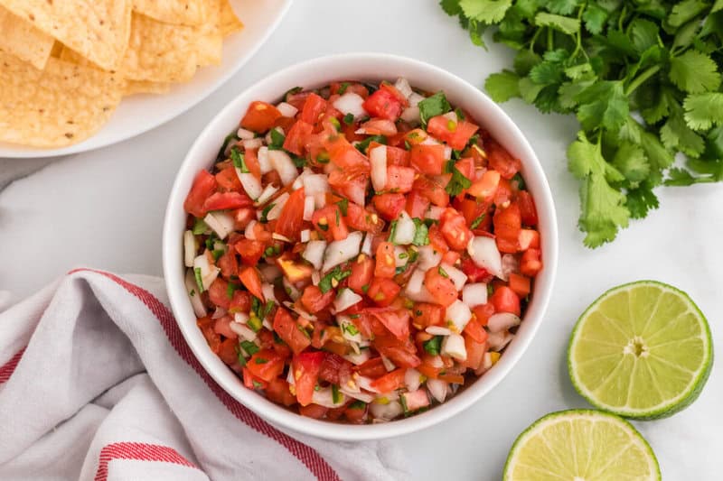 Pico de Gallo served in a white bowl with tortilla chips.