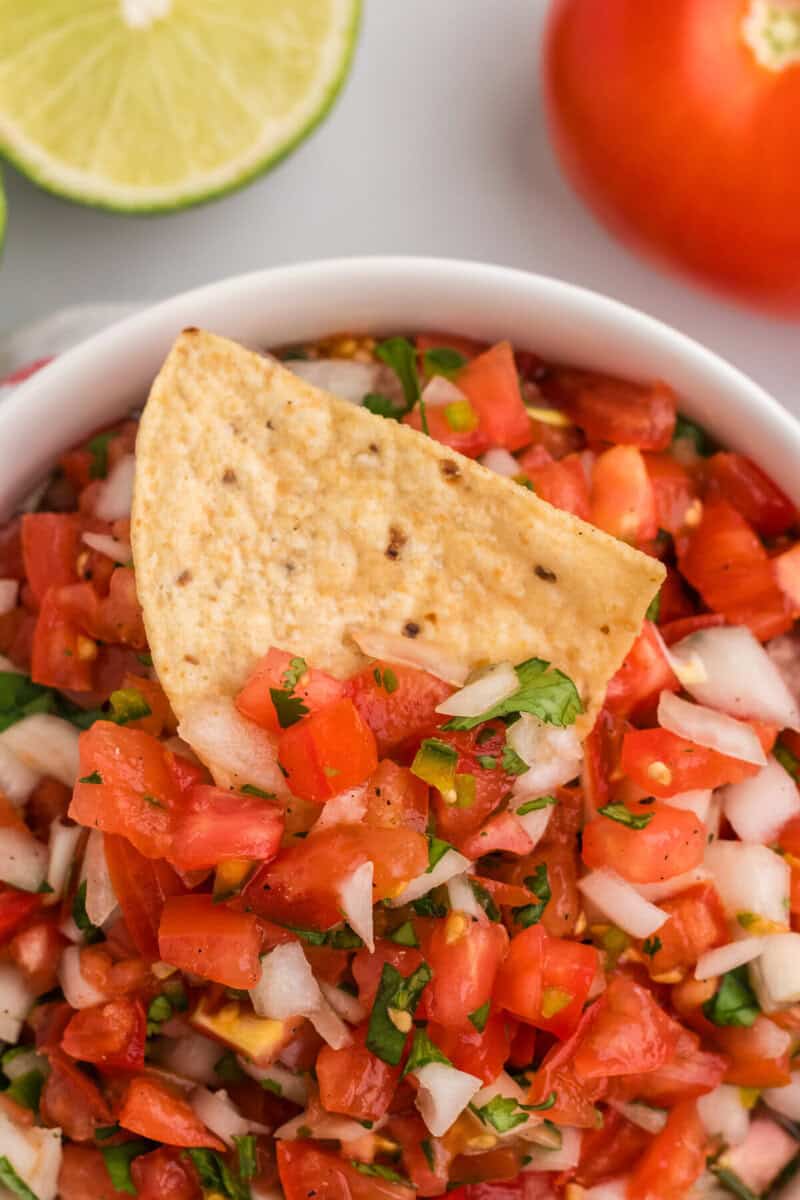 closeup of dipping a tortilla chip into the Pico de Gallo.