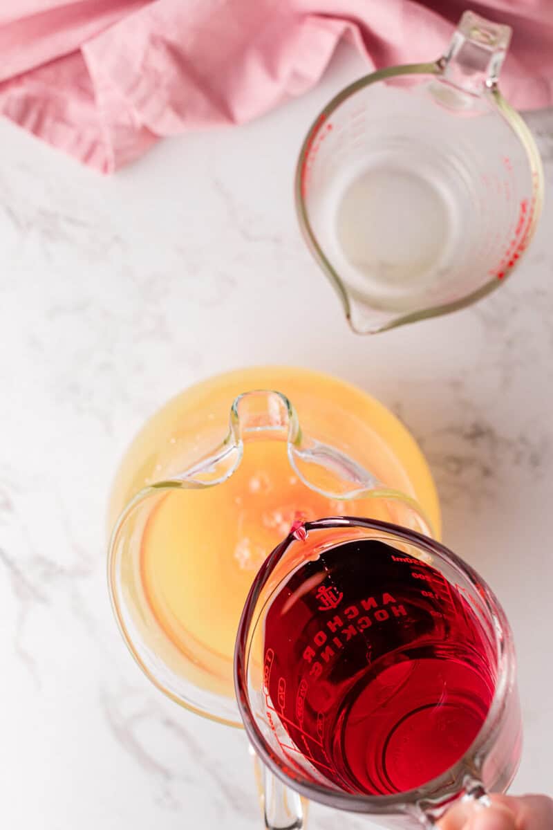 pouring the cranberry juice into the lemonade.