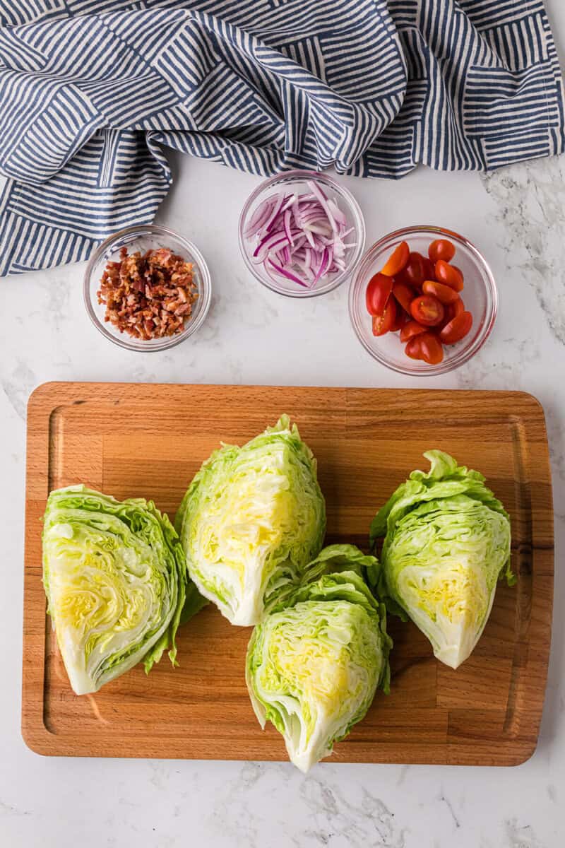 iceberg wedges on a wooden board with the other ingredients in bowls.