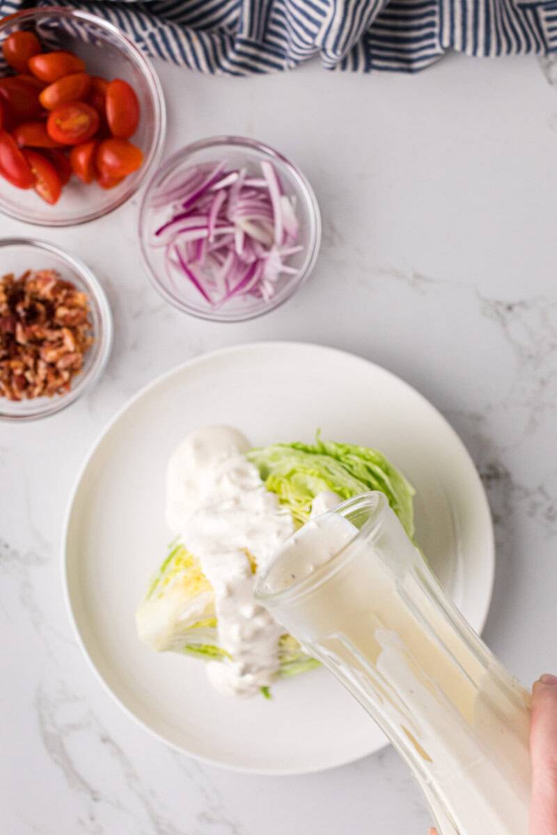 pouring the dressing on top of an iceberg wedge.