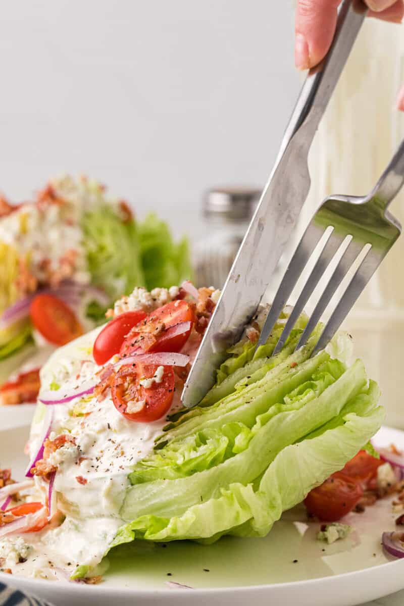 using a fork and knife to cut the Wedge Salad.