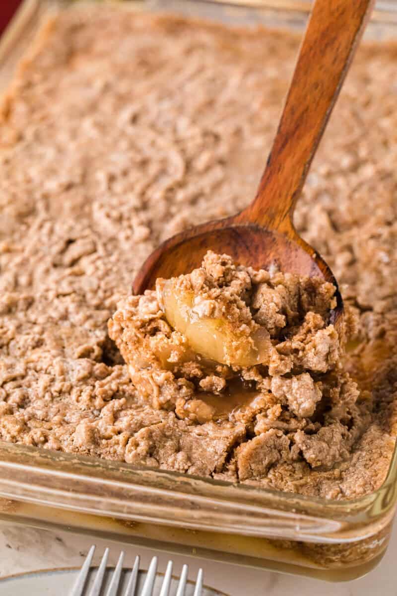 serving the Apple Spice Dump Cake with a wooden serving spoon.