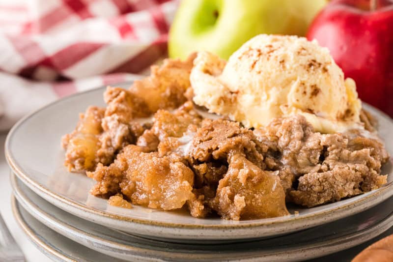 serving of the Apple Spice Dump Cake on stacked plates with vanilla ice cream.
