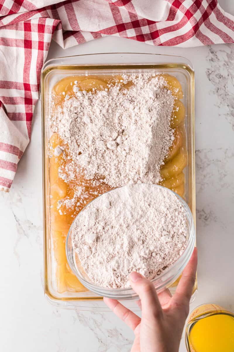 sprinkling the cake mix on top of the apple pie filling.