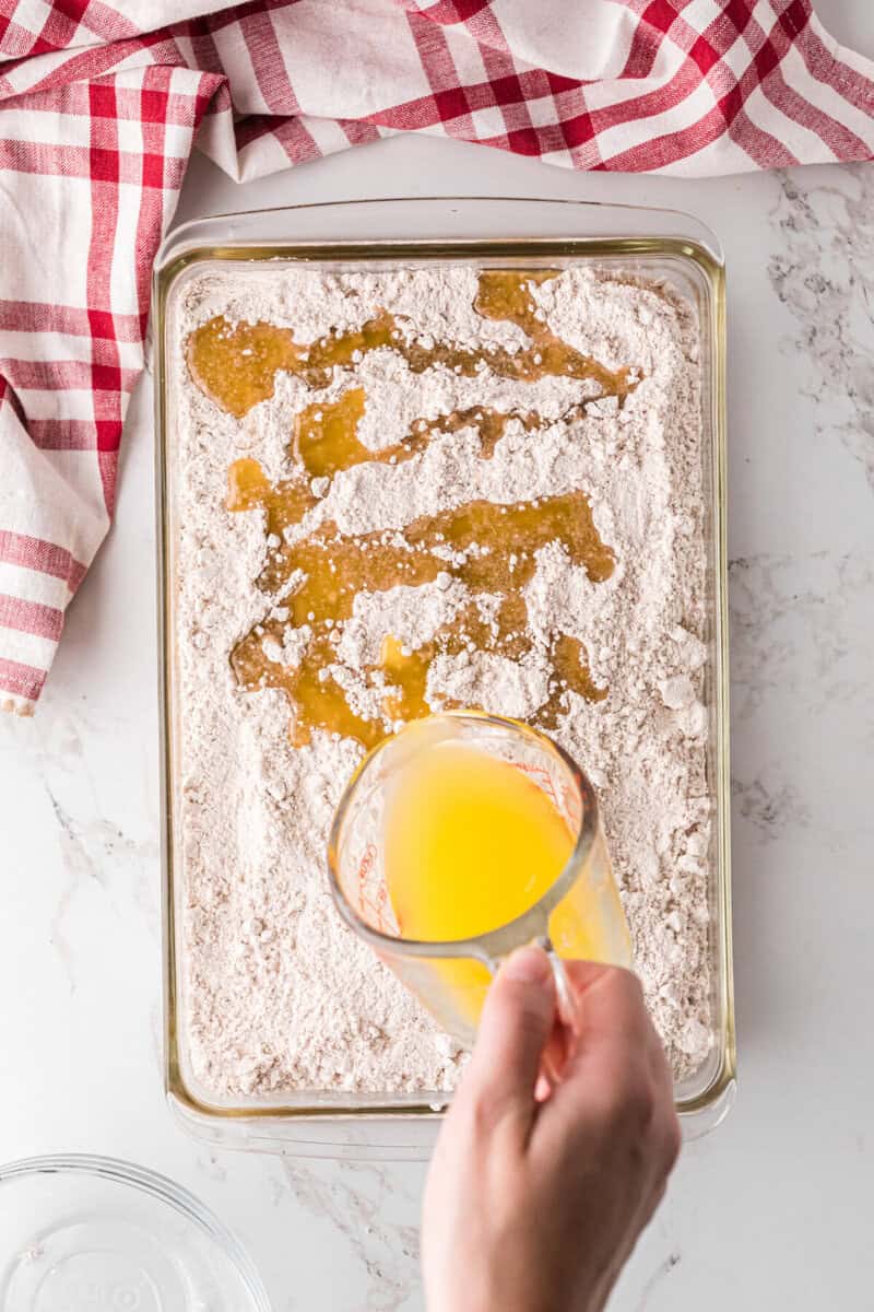 pouring the melted butter on top of the cake mix.
