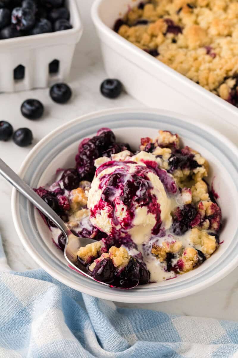 using a spoon to eat the blueberry cobbler.