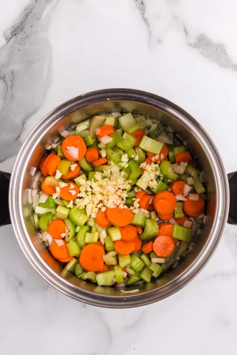 adding the minced garlic to the vegetables.