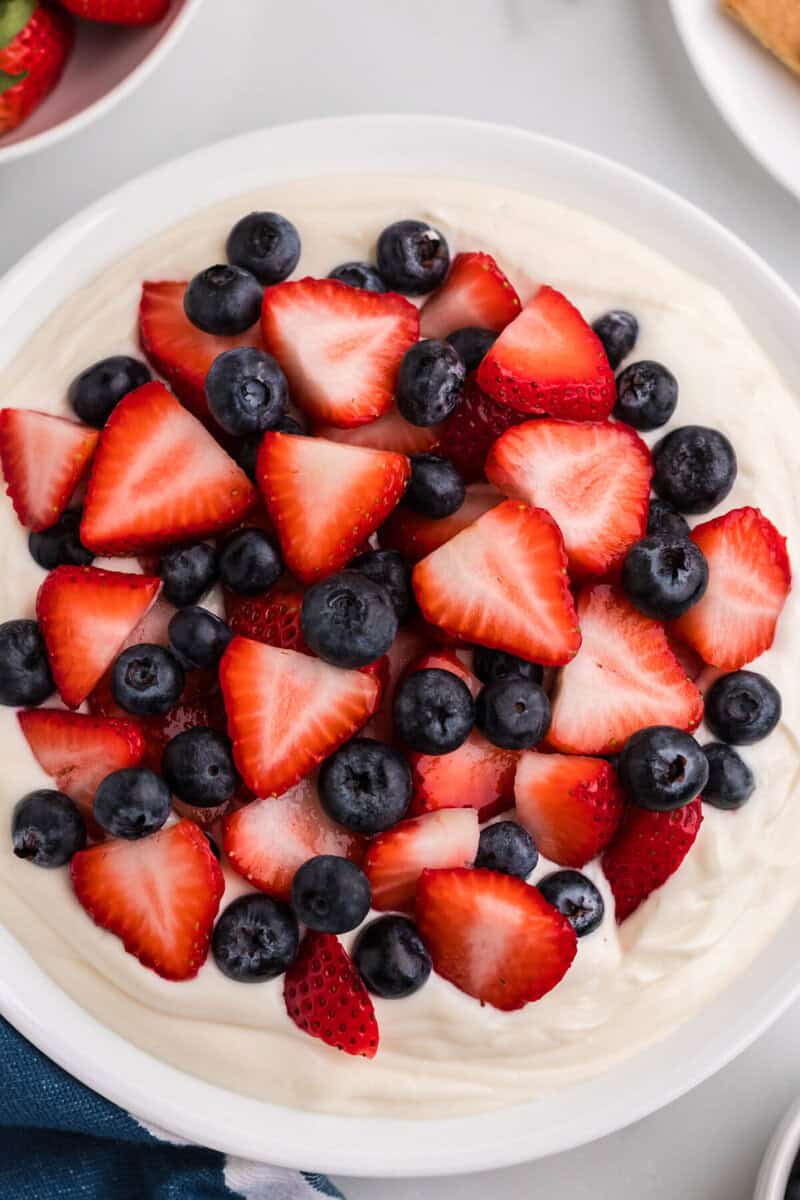 adding the strawberries and blueberries to the Patriotic Cheesecake Dip.
