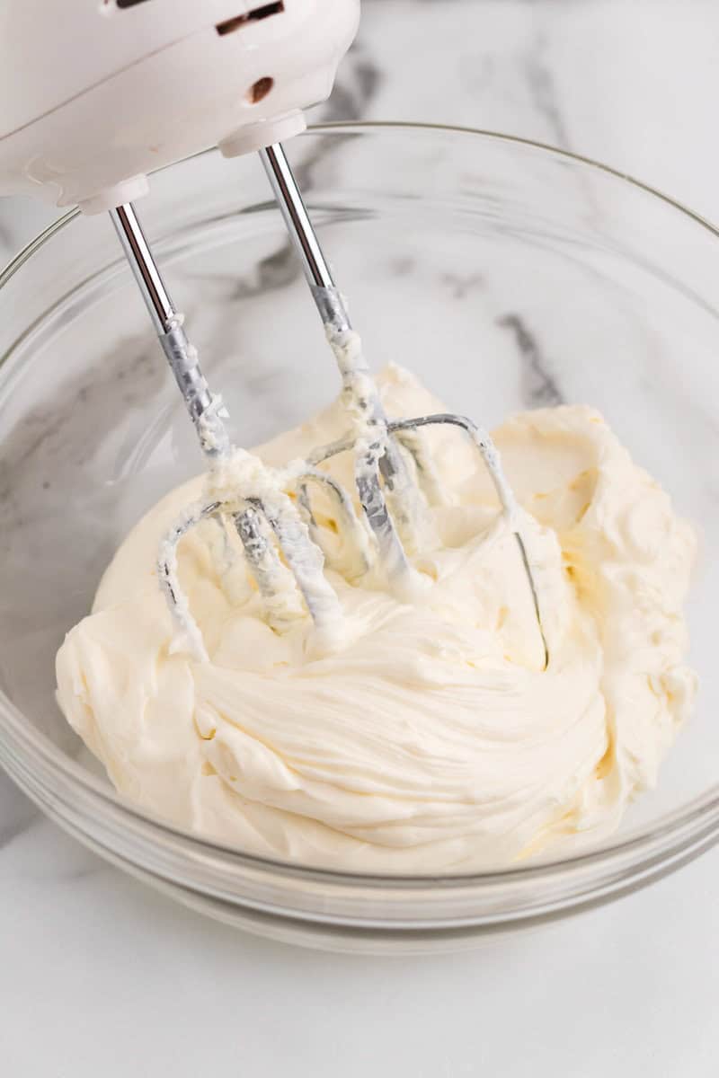 using a hand mixer to mix together the cheesecake dip.