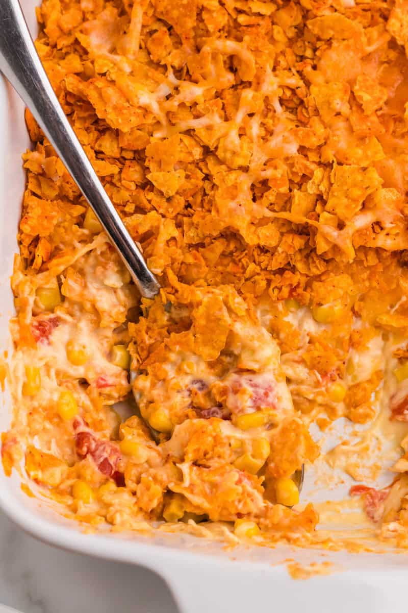 serving the Dorito Chicken Casserole with a metal spoon.