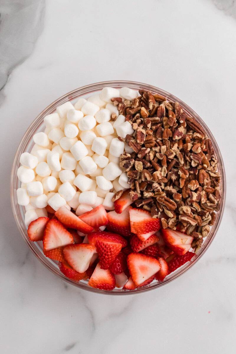 adding in the strawberries, pecans and marshmallows to the Jell-O.