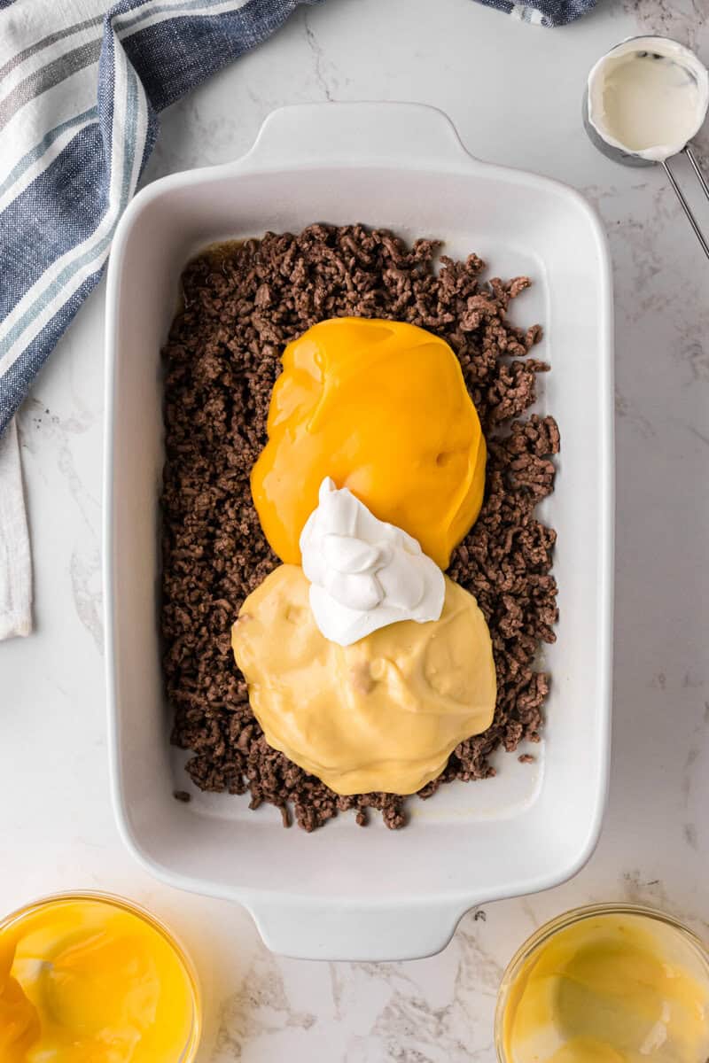 adding the additional ingredients to the beef to make the casserole.