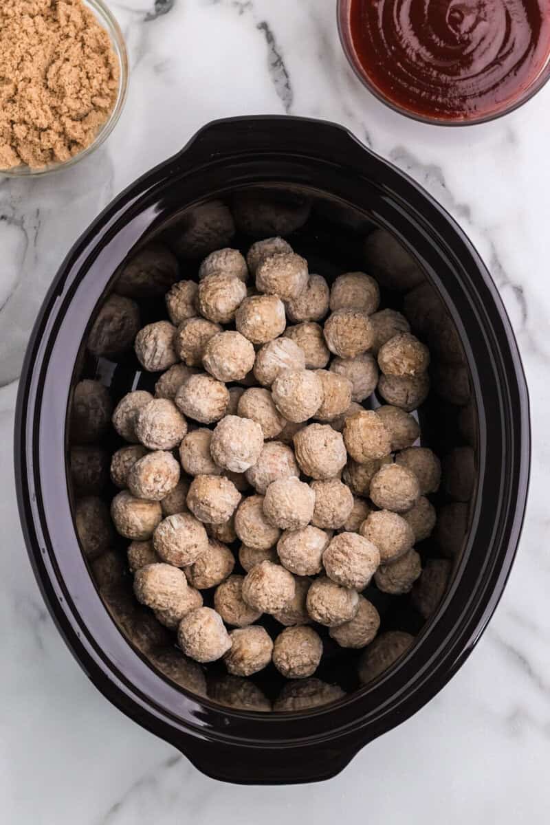 frozen meatballs placed in the slow cooker.