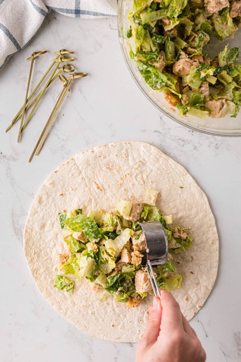 scooping the Chicken Ceasar filling onto the wrap.