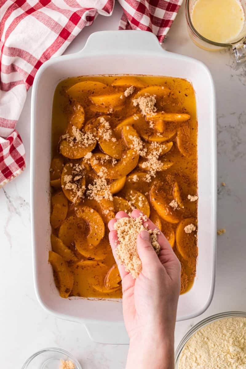 sprinkling the brown sugar on top of the peaches.