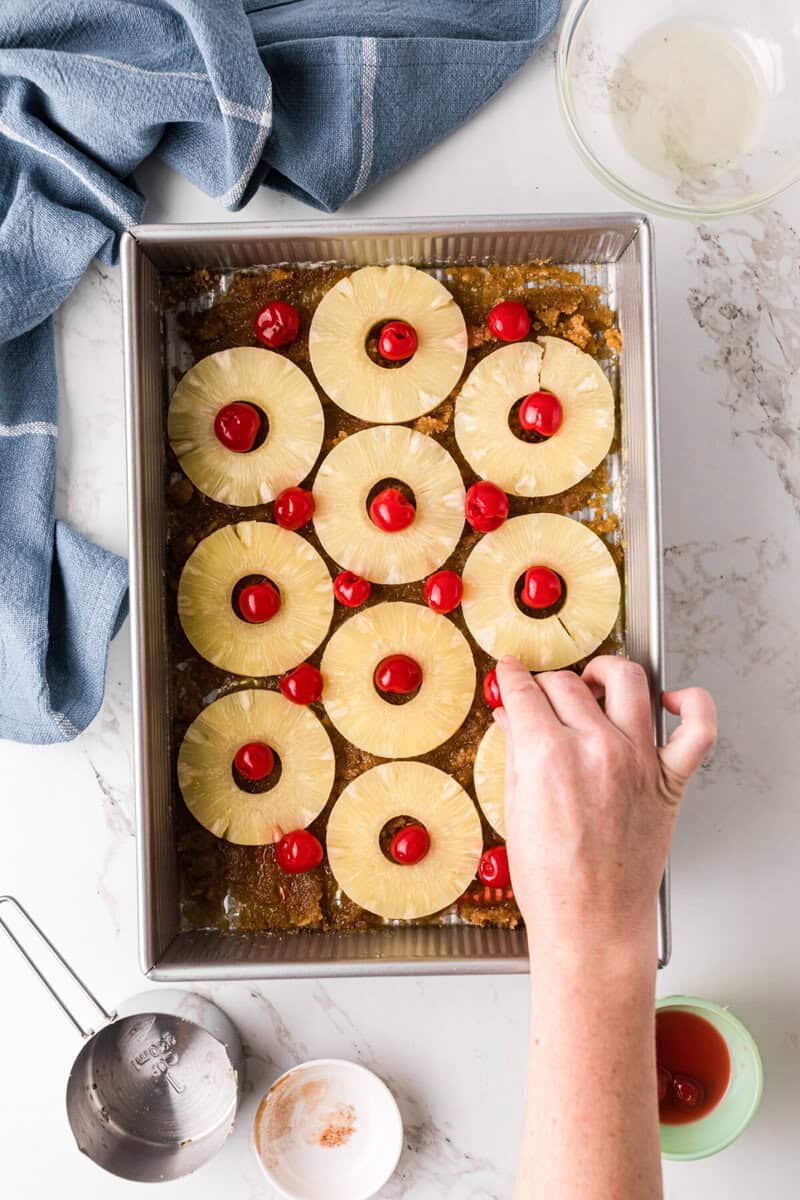 adding the pineapples and cherries to the pan.